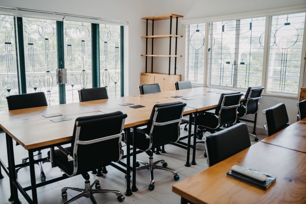 Spacious modern office conference room with black chairs and wooden tables.